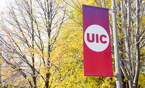A colorful UIC banner in front of some trees with yellow leaves.