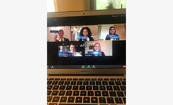 A laptop open to a Zoom call on the screen with men and women participating in an activity.