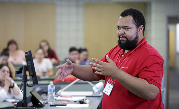 A UIC Business staff member standing at the front of the room talking to people sitting around the room.