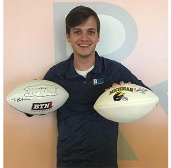 Nicholas Medline, MBA student, holding two footballs in his hands 
