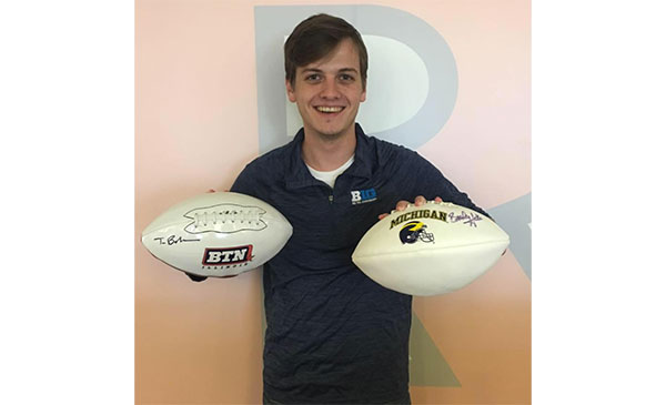 Nicholas Medline, MBA student, holding two footballs in his hands