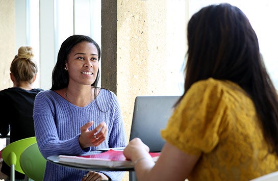 Two UIC students sitting at a table and talking