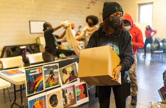 Mercedes Pickett, founder of Earth's Remedies, carrying a box at the Earth's Remedies Holiday for the West Side Community event