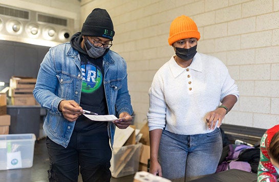 UIC Business alumnus Charles Pickett '17, standing next to another individual at the Earth's Remedies Holiday for the West Side community event