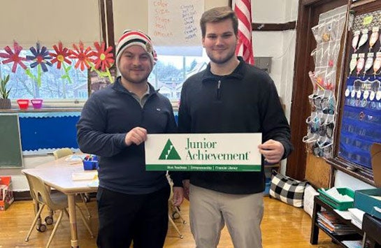 UIC Business students holding a Junior Achievement sign