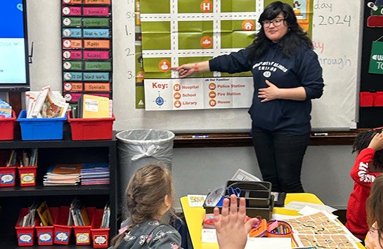 A UIC Business student teaching elementary school children as part of a Junior Achievement of Chicago volunteer service project